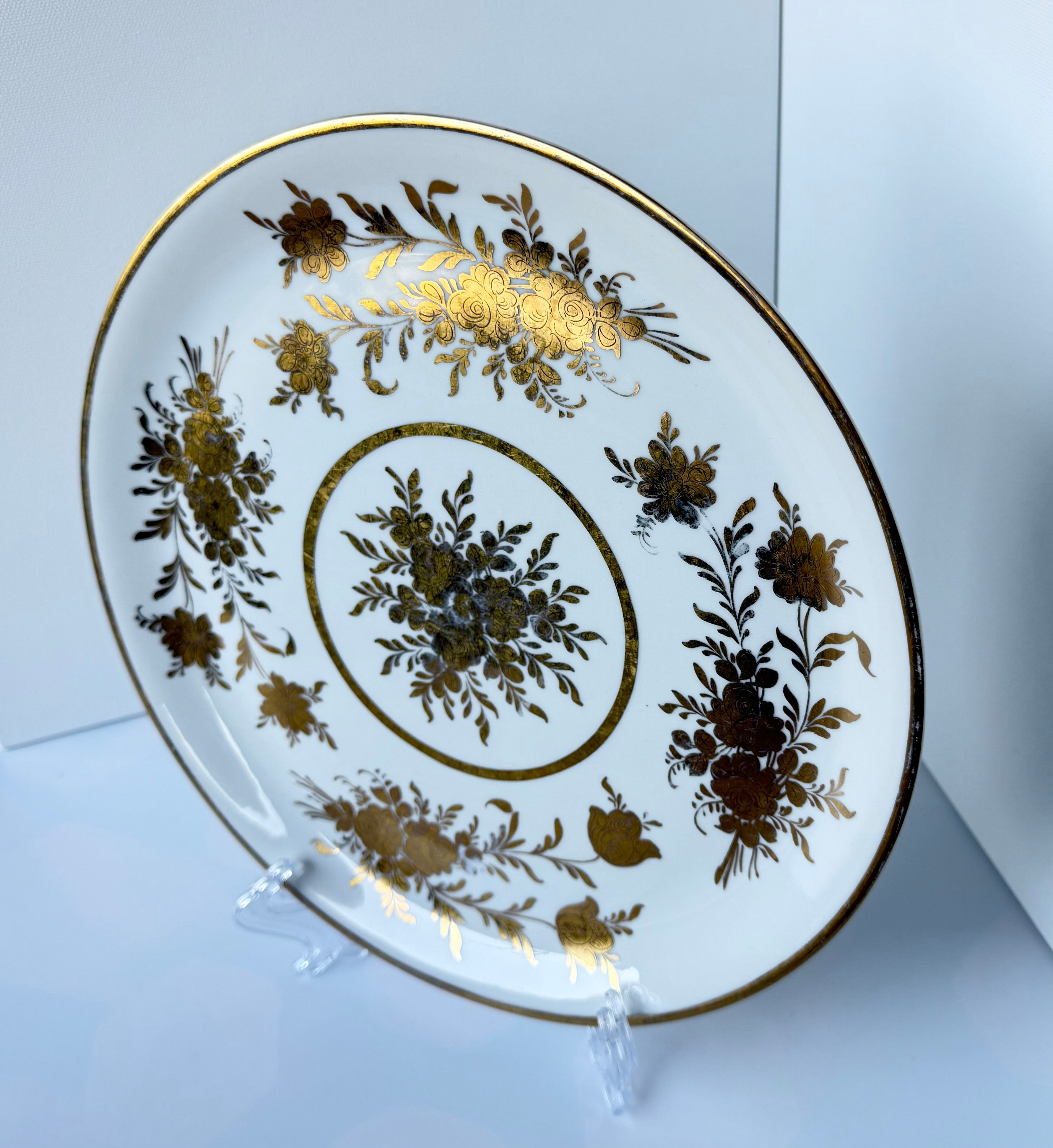 Antique French porcelain cake plate, from Paris, teaturing intricate hand-decorated gold floral motits on a white background.