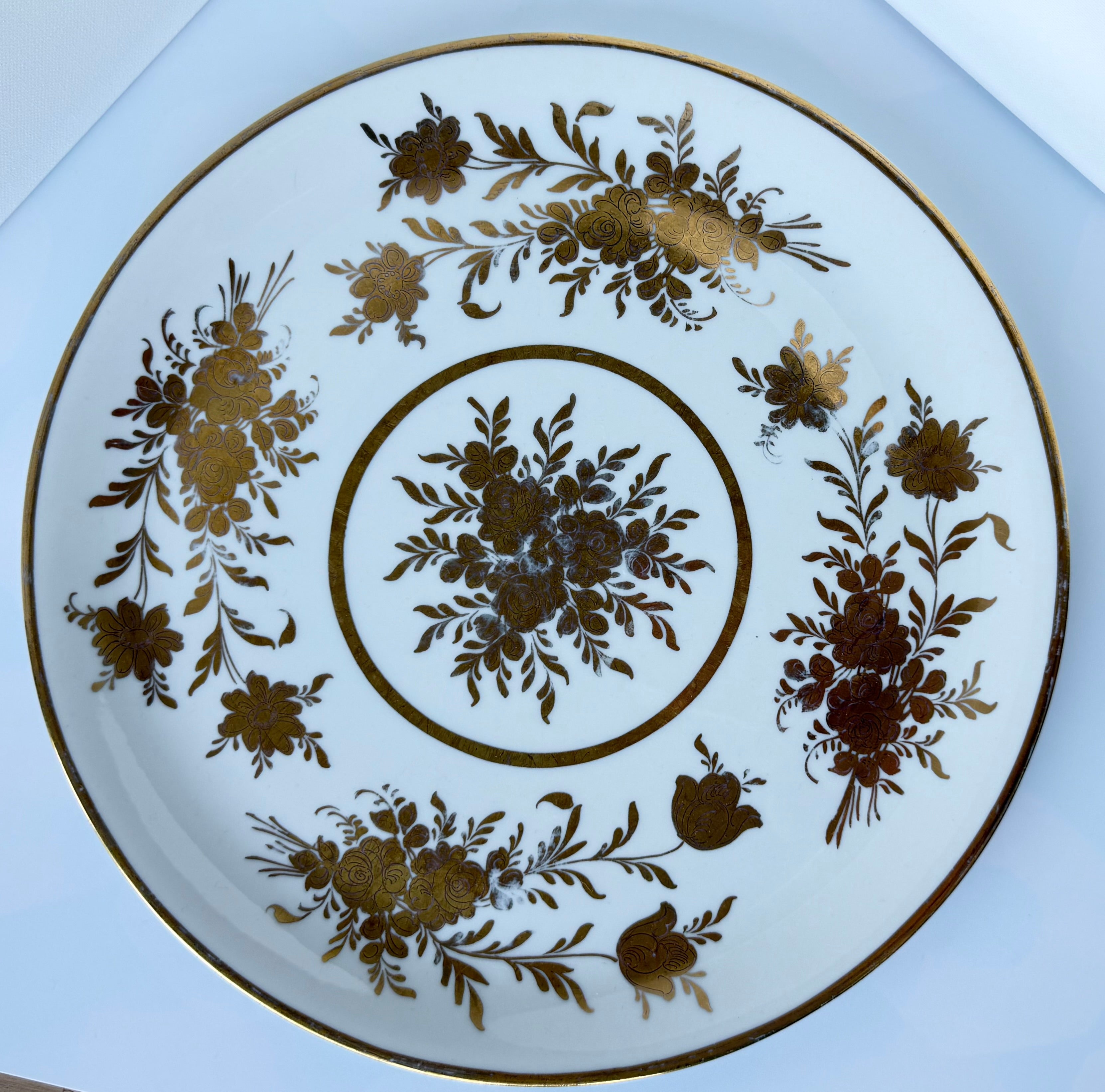 Antique French porcelain cake plate, from Paris, teaturing intricate hand-decorated gold floral motits on a white background.