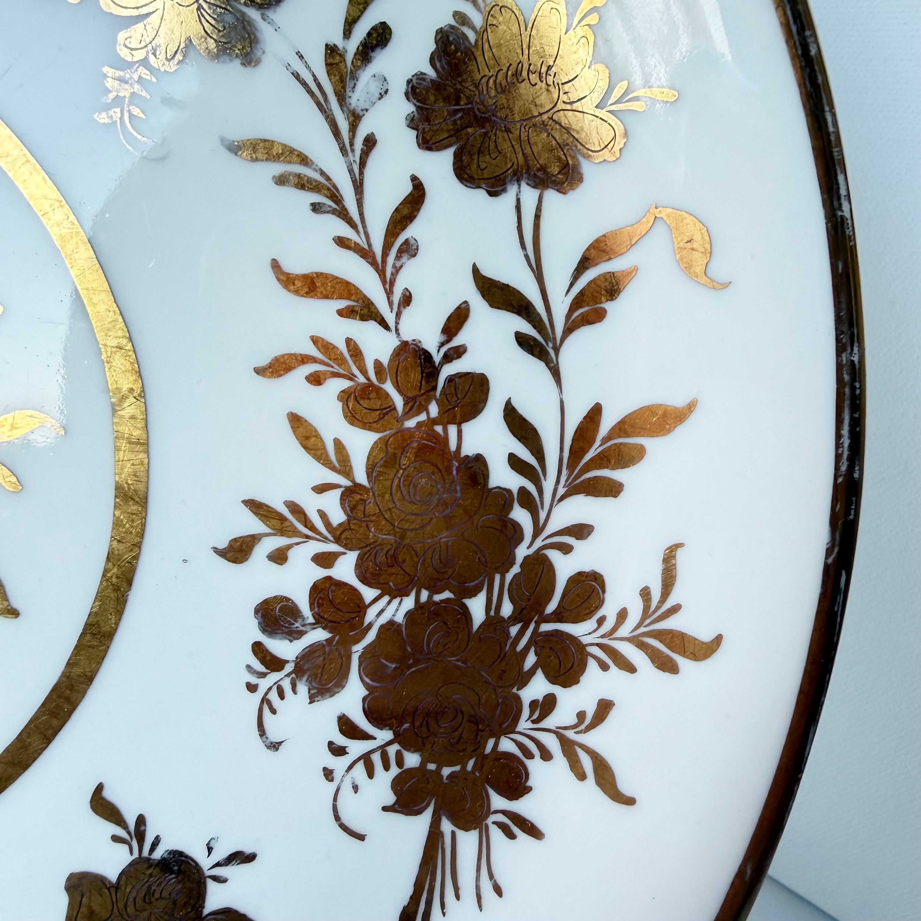 Antique French porcelain cake plate, from Paris, teaturing intricate hand-decorated gold floral motits on a white background.